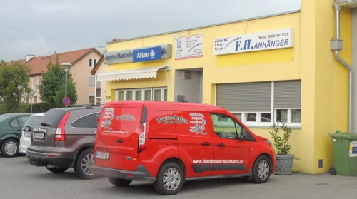 Gelbes Bürogebäude von F.H. Anhänger mit rotem Lieferwagen