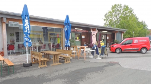 Holzgebäude mit Terrasse, Tischen und Sonnenschirmen im Gewerbepark
