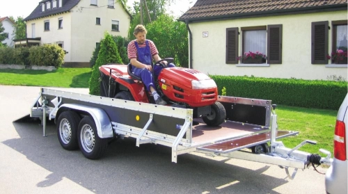 Rasentraktor fährt über die Rampe auf einen Tandemanhänger